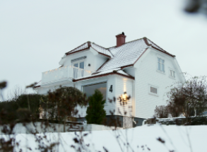 hvit enebolig i hage og snø på taket